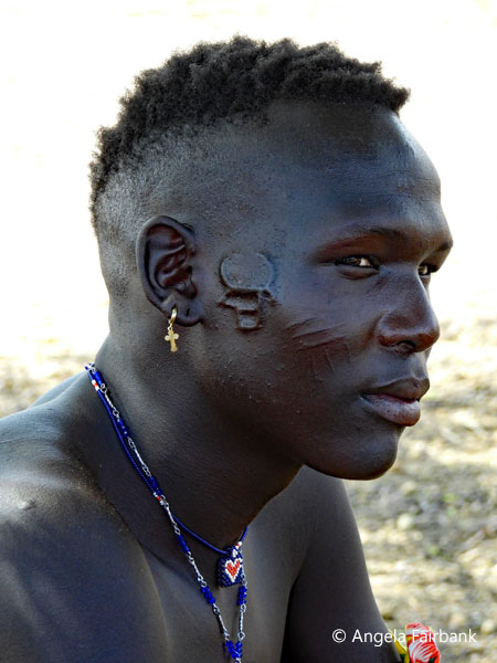 young Toposa man showing us his bull head cheek scarification 2