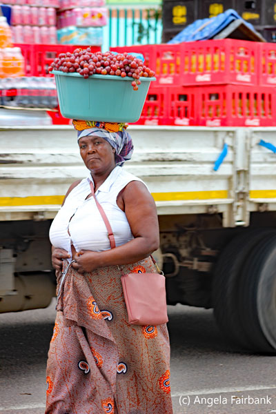 woman carrying basket of grapes on her head