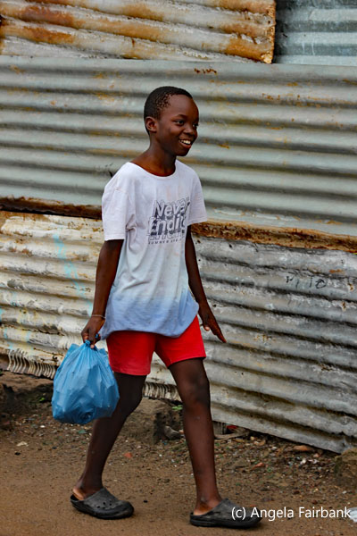 boy carrying blue plastic bag