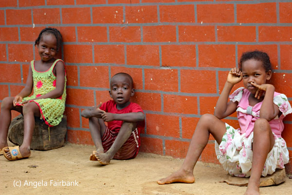 3 children sitting against wall