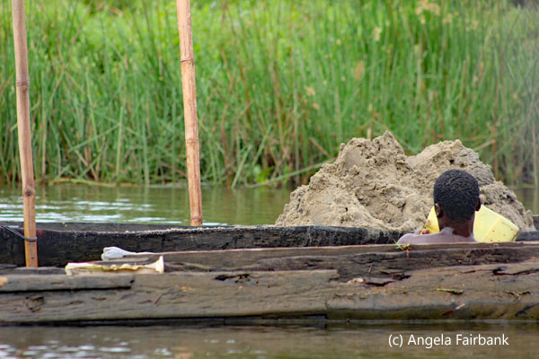 boy bringing up bucket of sand from bottom of river